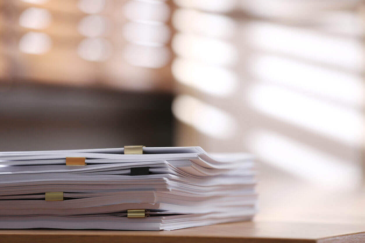 Stack of blank paper with binder clips on wooden table indoors