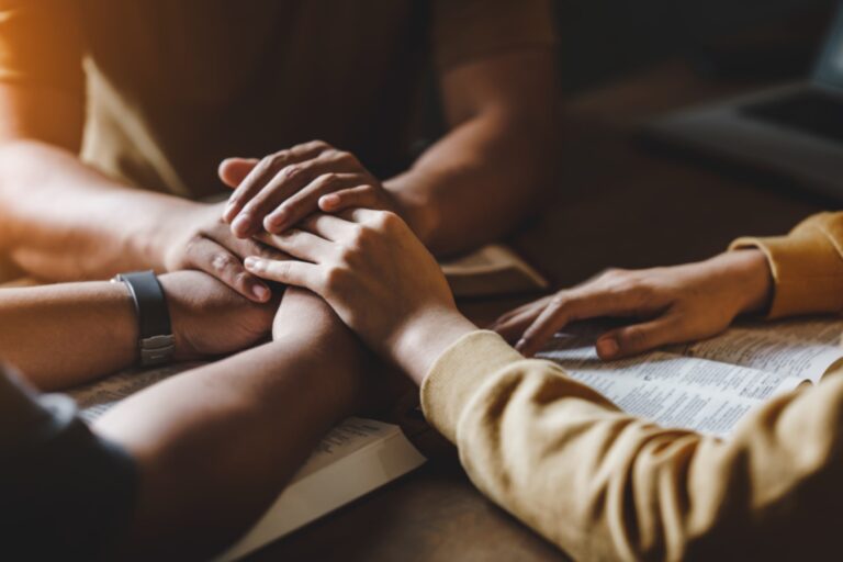 Three people holding hands above the table