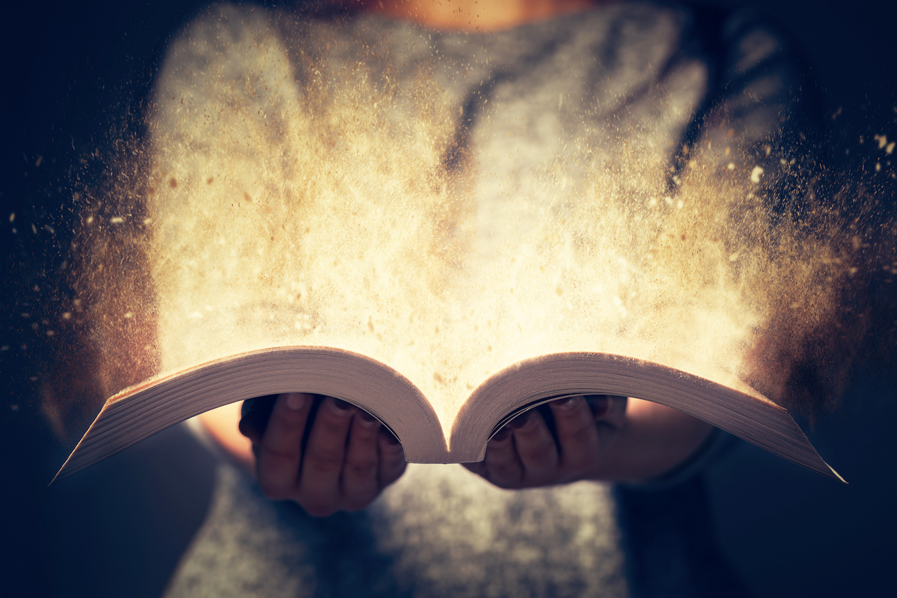 Woman holding an open book with two hands. Light coming out of the book as a concept of learning, education, knowledge and religion (Woman holding an open book with two hands. Light coming out of the book as a concept of learning, education, knowledge